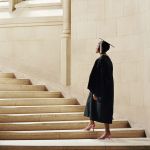 College student cap and gown walking up stairs